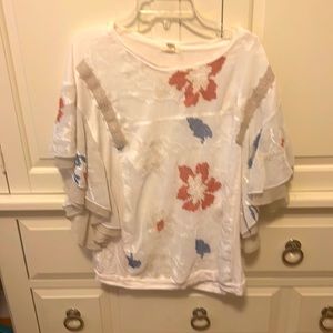 White blouse with red, blue , and beige embroidery. Dolman sleeves.
